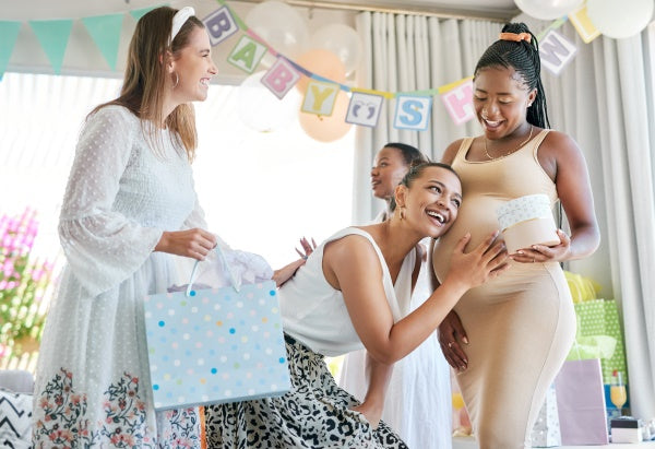 Group of women at a baby shower with a baby shower banner in the background.